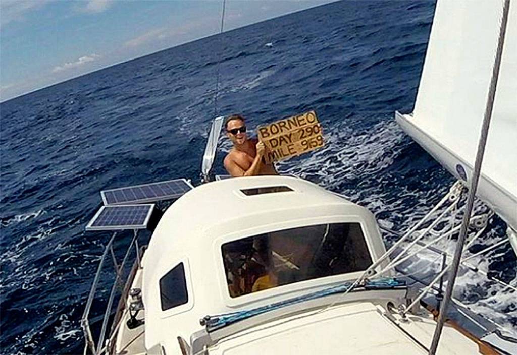 Andy Stephens holds up a sign that says Borneo, Day 290, Mile 9159. (Andy Stephens)