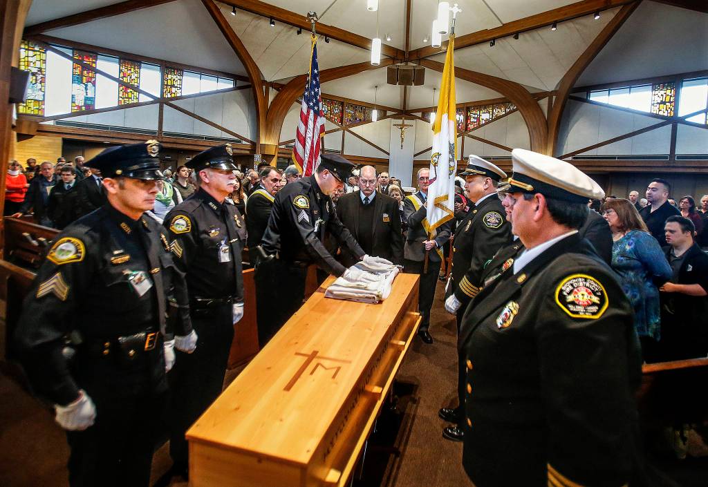 Monroe police officers (left) and Snohomish County Fire District 7 firefighters (right) prepare to move Sister Barbara Geibs casket to a gathering room just off the sanctuary at St. Mary of the Valley Catholic Church in Monroe Thursday. Geib was a longtime chaplain with Monroe police and fire departments. (Dan Bates / The Herald)