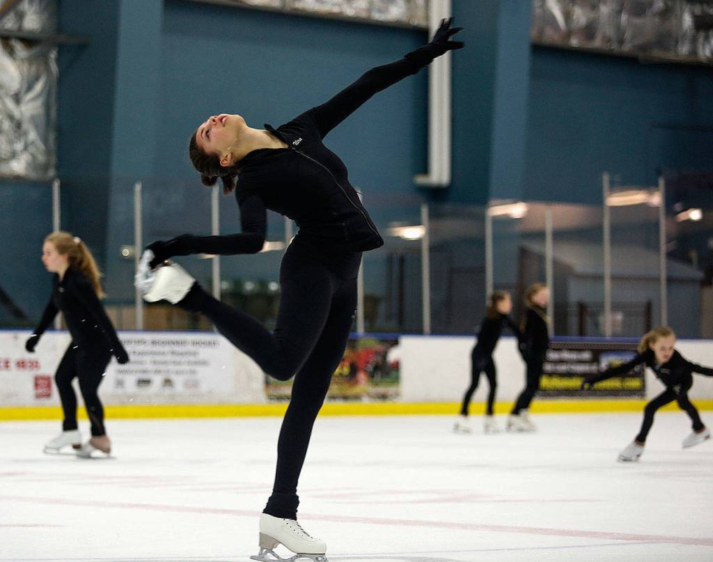 Nira Barlow, 16, grabs her skate in a move while practicing Thursday at Everetts Community Ice Rink. (Dan Bates / The Herald)