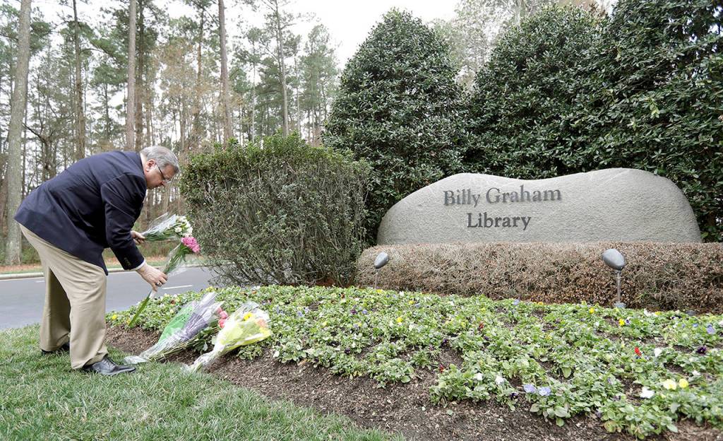 Billy Graham Library employee Howard Sharpe places flowers from visitors outside the entrance of the Billy Graham Library in Charlotte, North Carolina, on Wednesday. (AP Photo/Chuck Burton)