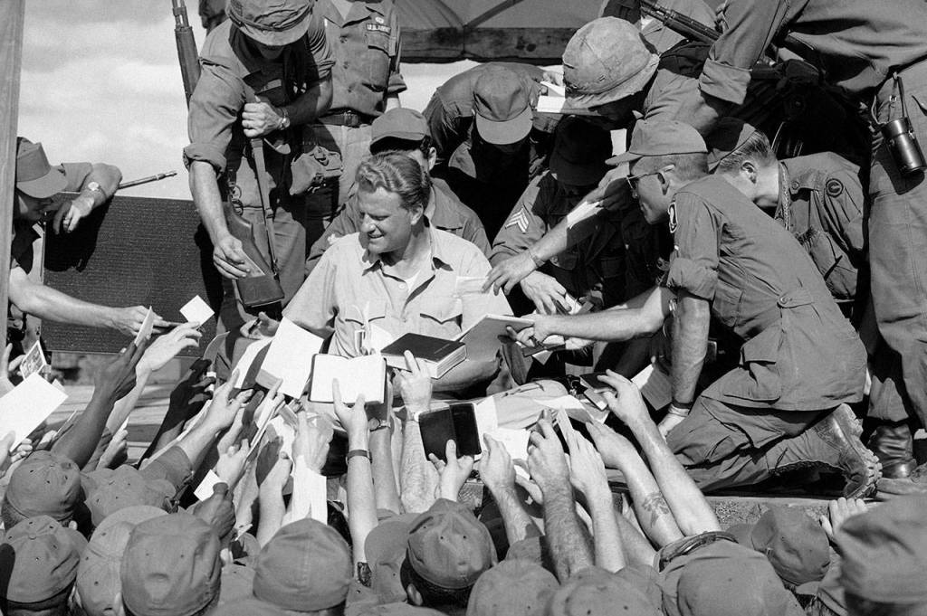 Scores of American GIs reach up to shake the hand and get his autograph after evangelist Billy Graham spoke to some 5,000 combat soldiers at the long Binh headquarters of field force II north of Saigon in South Vietnam on Dec. 22, 1966. (AP Photo)