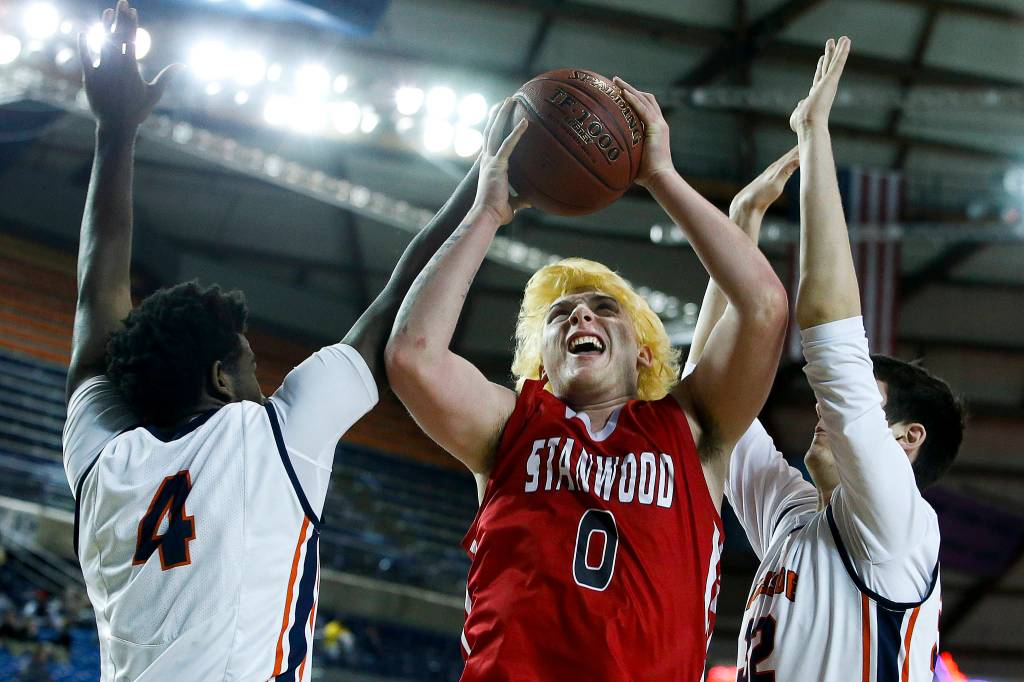 Stanwoods Mitchell Jones (0) takes a shot as Eastside Catholics Orlando Ashford (4) and Thomas Binz defend during a boys 3A state tournament game at the Tacoma Dome on Wednesday, Feb. 28. Eastside Catholic went on to defeat Stanwood 63-37. (Ian Terry / The Herald)