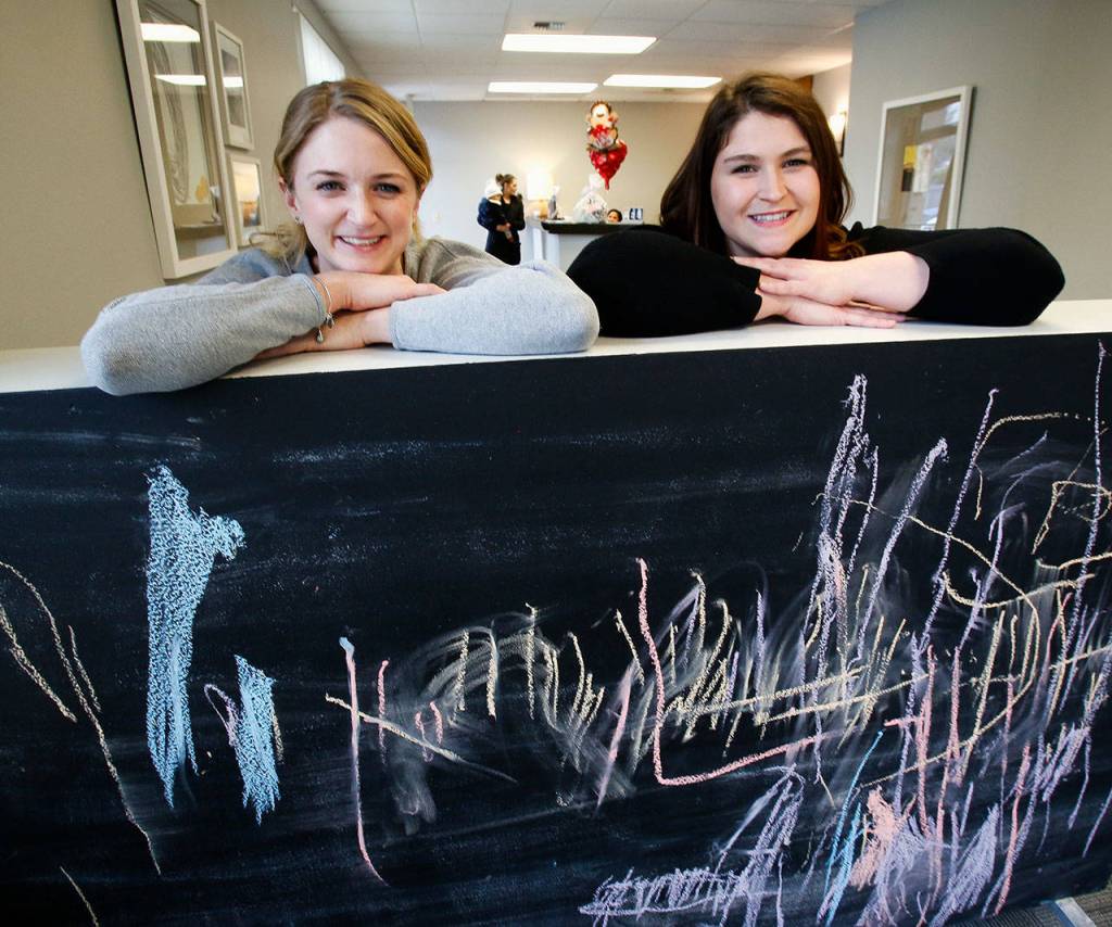 Viewed here in a childrens waiting area, complete with chalk scrawlings on a blackboard, longtime friends BreAnne Marcucci (left) and Jennifer Millich. Marcucci graduated from Mariner High School, as did another friend, Katrina Craddock (background) running the office. Pacific Wellness and Lactation provide postpartum and newborn care, as well as breastfeeding support. (Dan Bates / The Herald)