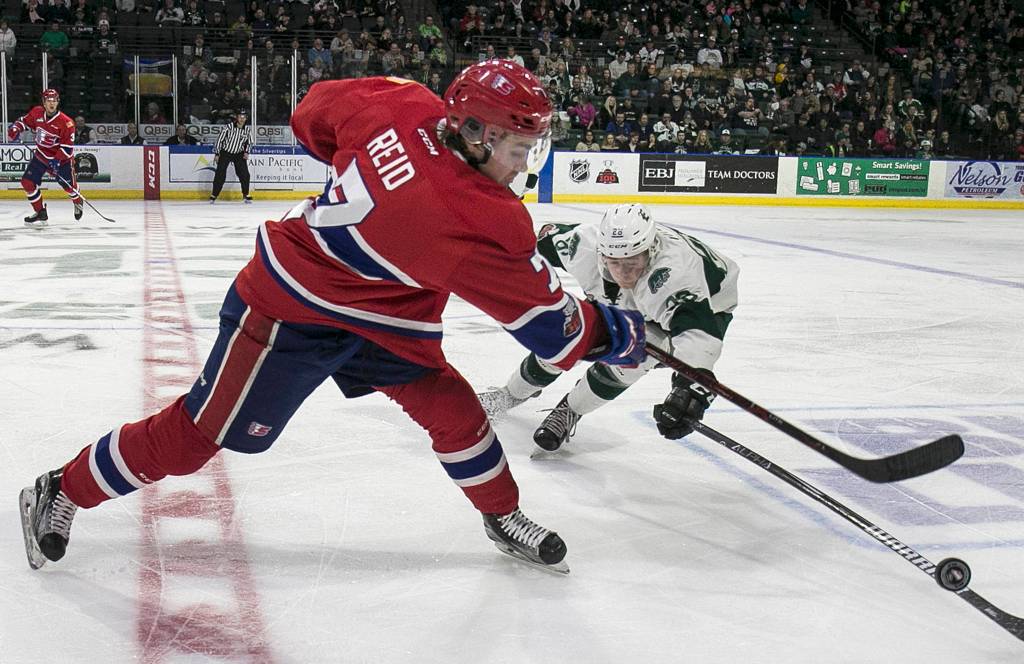 Spokanes Nolan Reid slaps the puck with Everetts Reece Vitelli defending at Angel of the Winds Arena in Everett on Feb. 25. (Kevin Clark / The Herald)