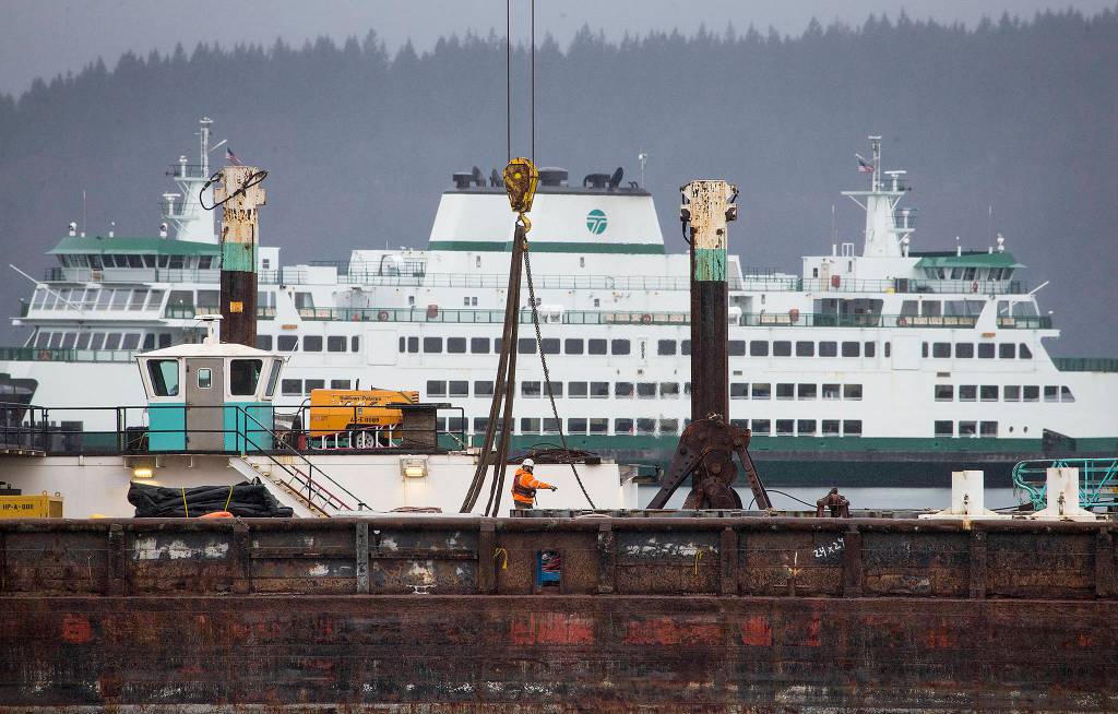 A worker directs others on a barge as construction continues at the new Mukilteo ferry dock on Feb. 28 in Mukilteo. (Andy Bronson / The Herald)