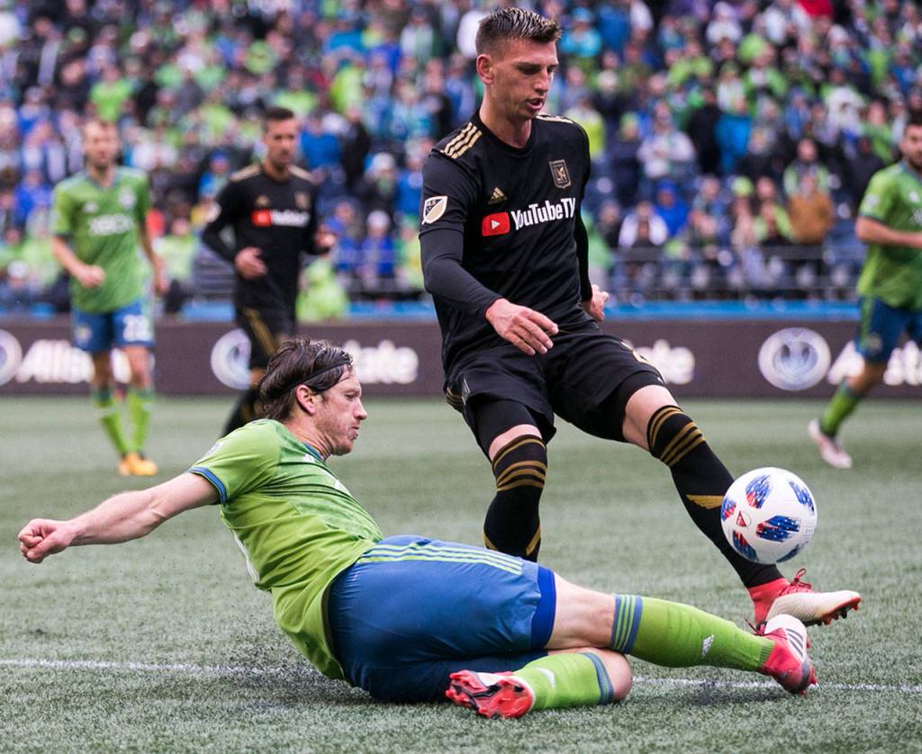 Sounders midfielder Gustav Svensson slides to advance with Los Angeles defender Tristan Blackmon defending on the Xbox Pitch at CenturyLink Field Sunday afternoon in Seattle on March 4, 2018. Los Angeles FC won 1-0. (Kevin Clark / The Daily Herald)
