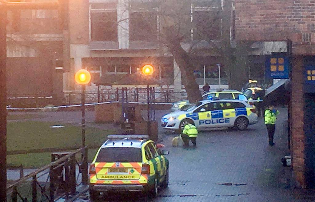 A police officer without any protective gear crouches down next to the bench in the Maltings Shopping centre, where Sergei Skripal and his daughter Yulia were found in Salisbury, England. (Thomas Belk/Solent News & Photo Agency via AP)