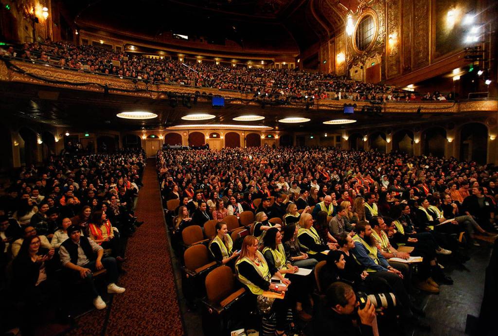 Orange and yellow-vested chaperones and high school students enough to pack the Paramount Theatre are treated to a question-and-answer session before getting to see Hamilton on Wednesday in Seattle. (Dan Bates / The Herald)
