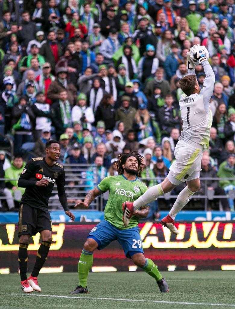 Los Angeles goalkeeper Tyler Miller gathers a shot with Sounders defender Román Torres (center) and Los Angeles Mark-Anthony Kaye (left) looking at CenturyLink Field on the Xbox Pitch in Seattle on March 4. Los Angeles FC won 1-0. (Kevin Clark / The Herald)