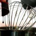 Frances Turner drips some red velvet extract into a white chocolate biscotti that she is mixing in her small mixer. (Dan Bates / The Herald)
