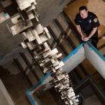 Everett Police Departments Aaron Snell stands in a stairwell Friday where an art piece by artist Keith Imus hangs down its center. Its hiding in a stairwell now that nobody sees, Imus says about his work. (Andy Bronson / The Herald)