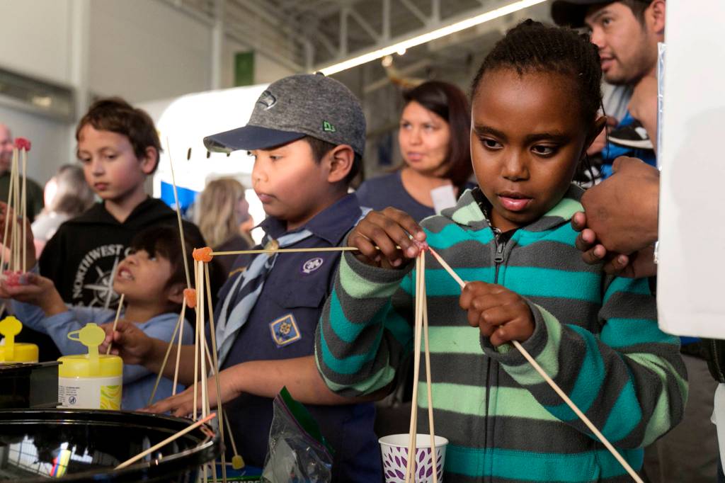 Lisa Karumba, 9, (right) works at the structural engineering booth Wednesday afternoon during the 2018 STEAM Family Night at The Future of Flight Aviation Center in Mukilteo on March 14. (Kevin Clark / The Herald)