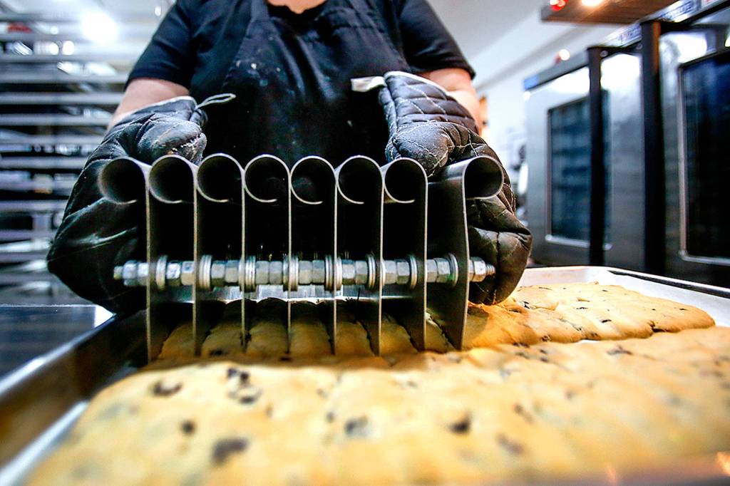 Instead of the standard single-blade cutter, Frances Turner cuts the large sheets of bicotti into exact sizes with a cutter her husband, a Boeing employee, designed and built for her. (Dan Bates / The Herald)