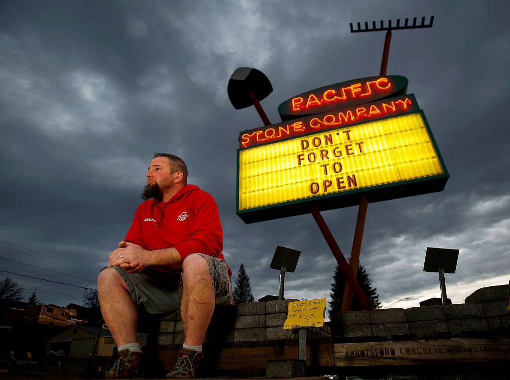 Pacific Stone Company manager James Martin enjoys a warm morning along Evergreen Way in Everett in front of his sign, <a href="http://www.heraldnet.com/news/readerboard-signs-bear-special-message/" target="_blank">Dont Forget To Open.</a> (Dan Bates / The Herald)