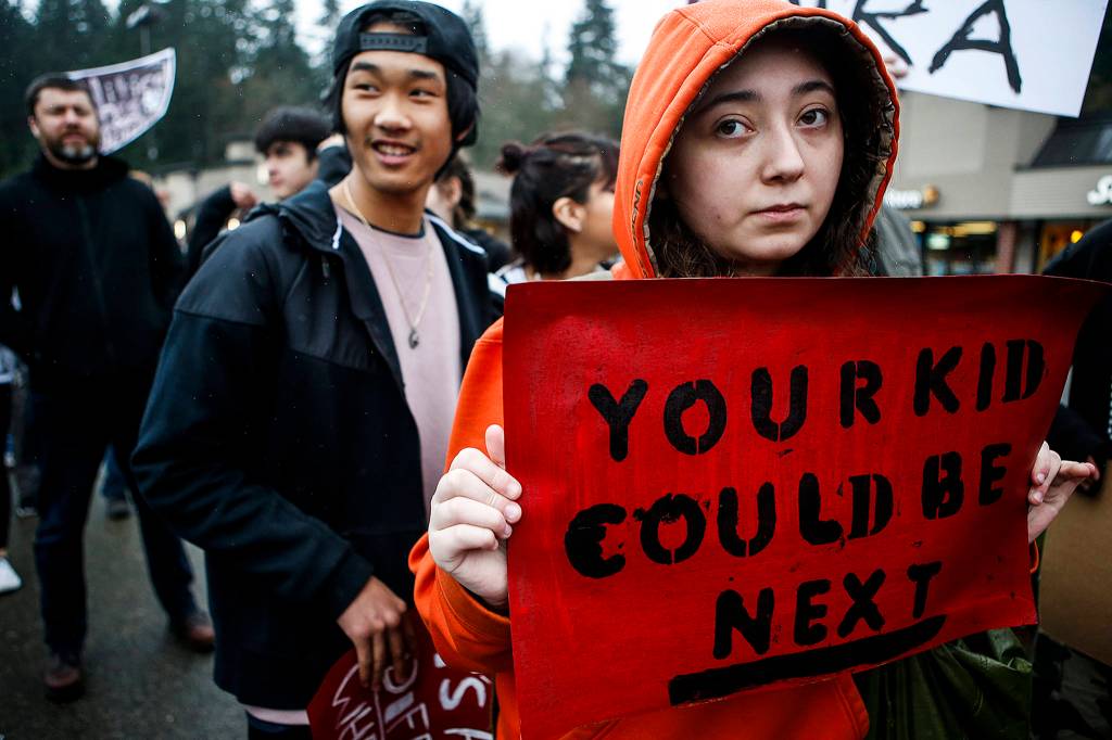 Sydni Hillman (right), a sophomore at Scriber Lake High School, walks out of school with other classmates to bring awareness of gun violence in schools on March 14 in Edmonds. (Ian Terry / The Herald)