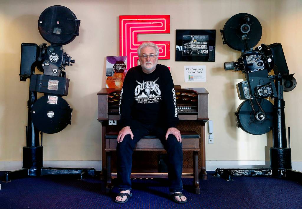 The Historic Everett Theatre is for sale, with an asking price of $2,450,000. Since 2014, brothers Craig and Curt Shriner have brought crowds to downtown Everett between music acts and films. Here, Curt Shriner sits at an organ between two vintage movie projectors in the lobby. (Dan Bates / The Herald)