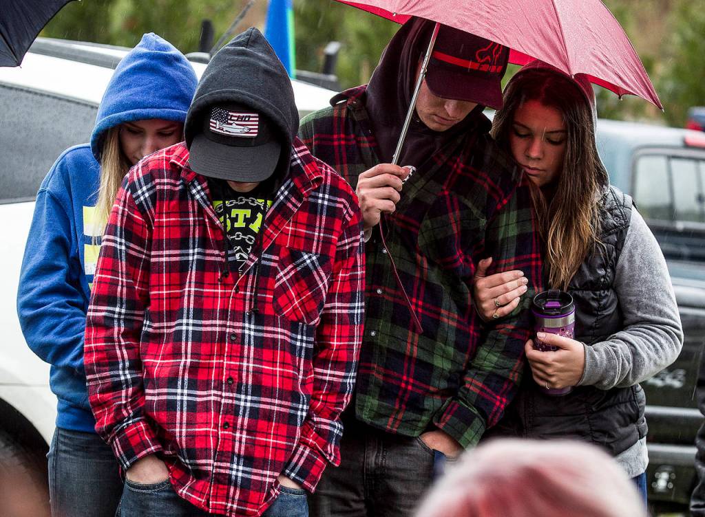 A closing prayer is read on Thursday as Shayla Wilgus (left), Zack Brunner (center left), Riley Brunner (center right) and Jeslyn Barry (right) bow their heads during a ceremony to honor victims on the four-year anniversary of the 2014 Oso mudslide. (Ian Terry / The Herald)