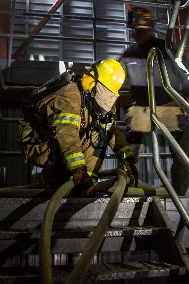 Andy Bronson / The Herald                                His face mask covered and hoses running under and over each other, Snohomish County Fire district 7 recruit Johnson Brooks tries to follow the correct fire hose up a stairwell during Snohomish Countys first fire training academy at the South County Snohomish Fire Rescue training ground training grounds Monday in Everett.