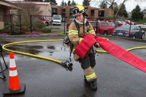 Marysville Fire Department recruit Katie Hereth eyes a cone, marking the finish line, as she hauls a 5-inch, 140-pound line 200 feet in Snohomish Countys first fire training academy obstacle course at the South County Snohomish Fire & Rescue training grounds Monday in Everett. (Andy Bronson / The Herald)