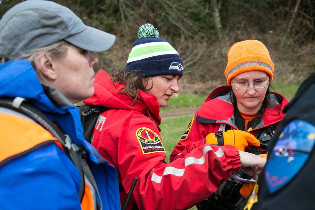 From left, Wendy Bowlin, Trina Eddy and Angela Jurdon look over a map of their search area. (Kevin Clark / The Daily Herald)