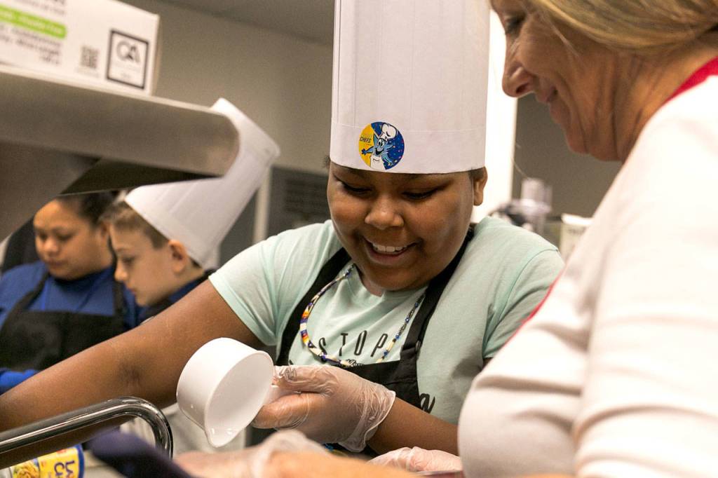 Monet Clements of Quil Ceda Tulalip Elementary measures and pours water, as co-chef Oma Fry looks on. (Kevin Clark / The Herald)