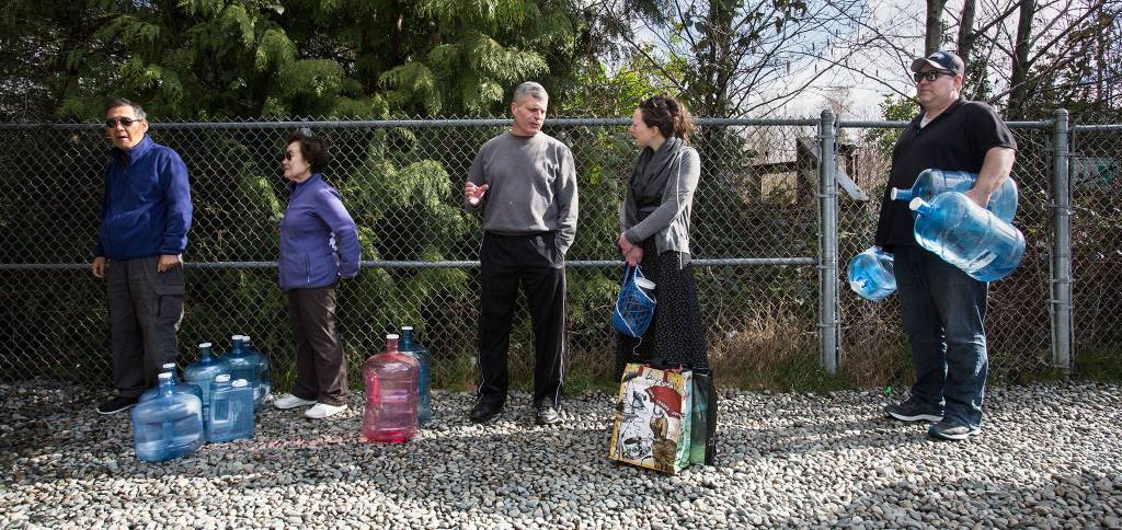 People wait in line to fill up various water jug and containers at the artesian well on 164th Street on Monday, April 2, 2018 in Lynnwood, Wa. The well," also known as Well No. 5 or the 164th Street Artesian Well is in excess of 400 feet in depth and is cased to approximately 120 feet. The well flows at a rate of about 10 gallons per minute. (Andy Bronson / The Herald)