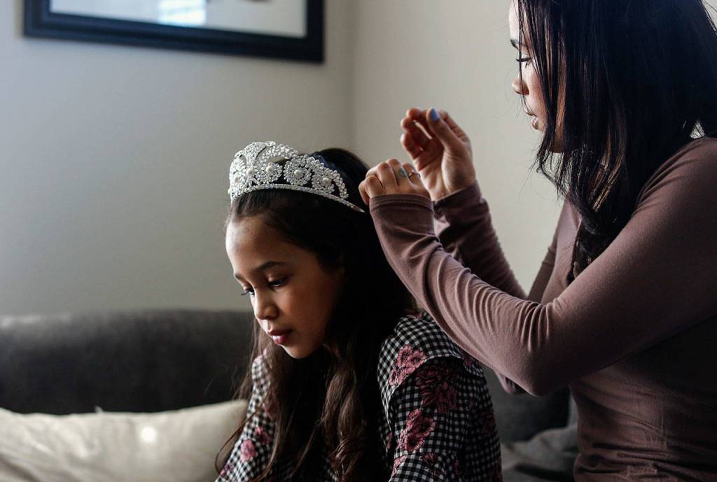 Paris Hansen helps her daughter Isabelle, 8, with her tiara. (Dan Bates / The Herald)