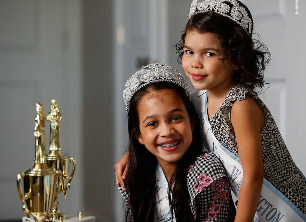 Isabelle Hansen, 8, (left) and Aria Hansen, 4, put on their tiaras and Miss Washington Princess sashes. The family is preparing for a big one in July. (Dan Bates / The Herald)