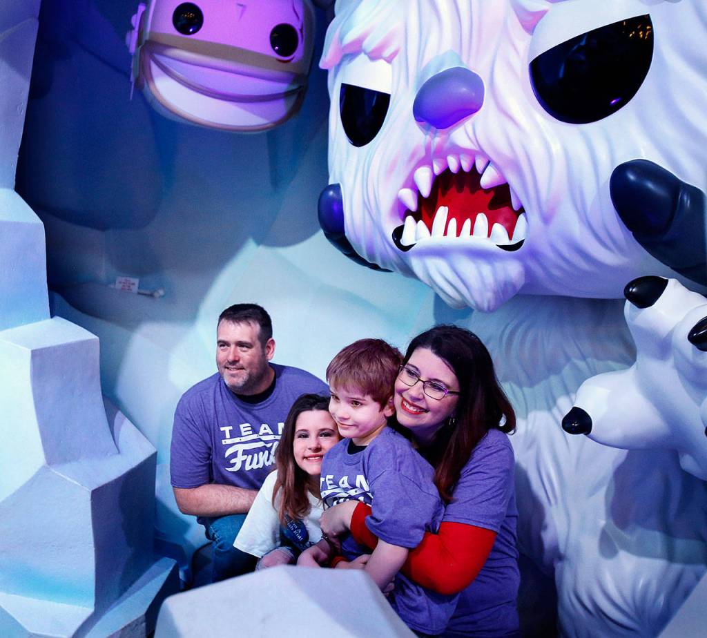 The Kemps sit together in a scary Star Wars cave while a Funko photographer takes a family portrait. From left are dad, Jason, Make-A-Wish kid Jayla, 11, Dylan, 6, and mom, Michelle. (Dan Bates / The Herald)