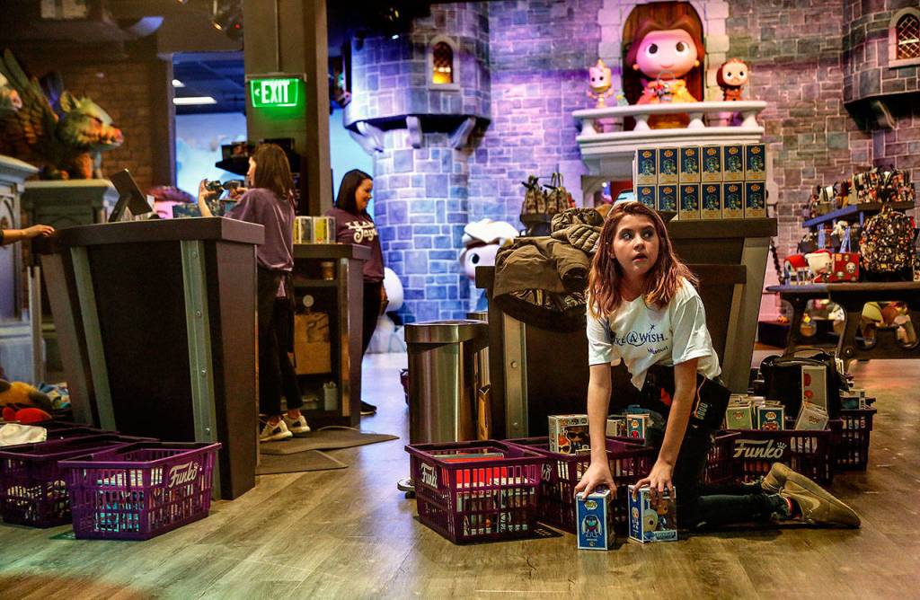 Jayla Kemp looks up from her shopping baskets of merchandise, which encircle the check-out counters at Funko, and are part of her Make-A-Wish. Her mom and dad and younger brother, Dylan, are going through more full baskets behind the other end of the counter. (Dan Bates / The Herald)