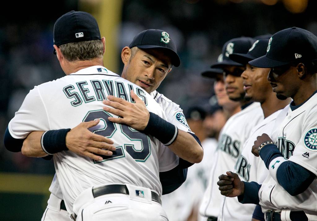 Ichiro Suzuki and manager Scott Servais embrace before the start of the home opener at Safeco Field in Seattle on March 29. (Kevin Clark / The Herald)