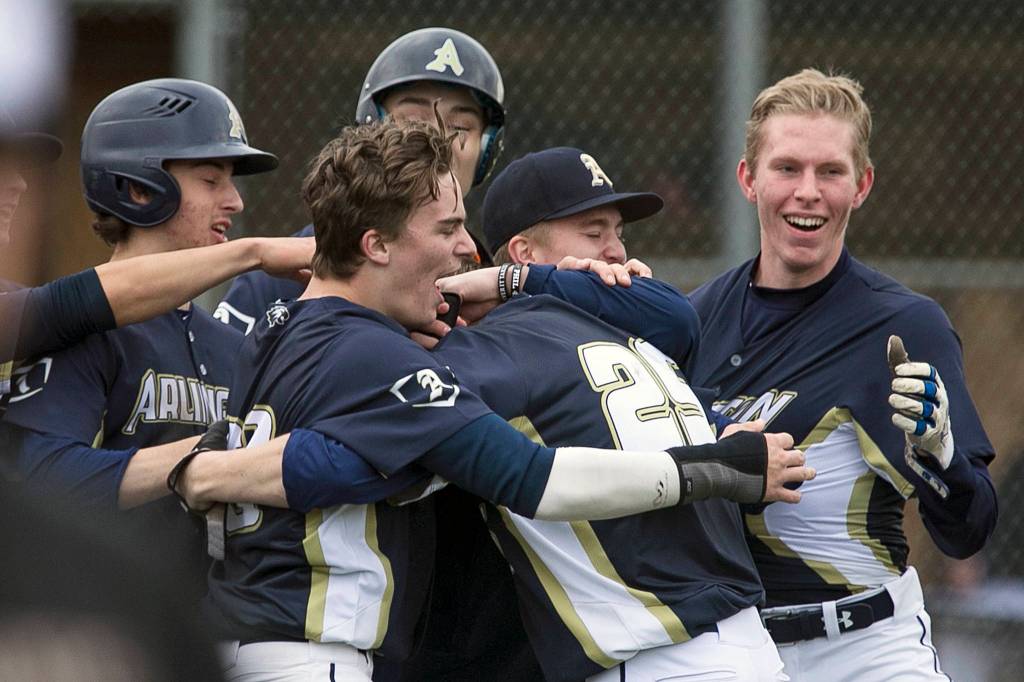 Arlington celebrates Cameron Smiths (25) game-winning RBI at Arlington High School on March 28, 2018. Arlington won 6-5. (Kevin Clark / The Herald)