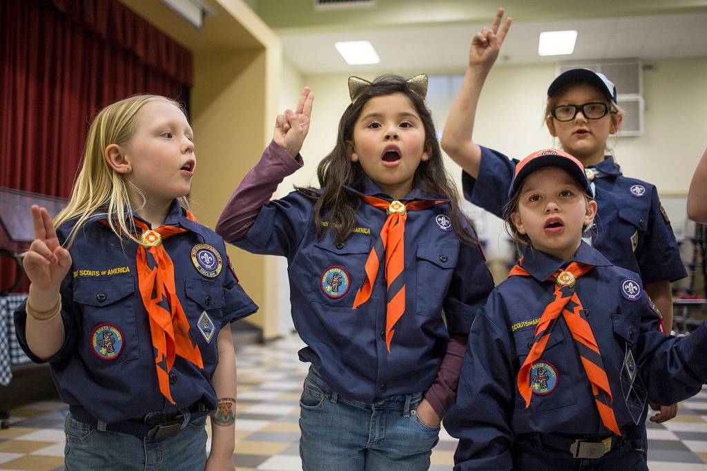 Cub Scout Grace Davis (left) recites the Scout Oath with other members of Troops 121 and 16 at Silver Lake Elementery on March 26 in Everett. Davis, 7, made history as the first registered girl Cub Scout in the Mount Baker Council. (Andy Bronson / The Herald)