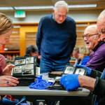 From left, library historian Lisa Labovitch, Jerry Solie (standing), and history buffs Dave Ramstad and William Vincent (right) enjoy one anothers light conversation while studying images in dozens of scrapbooks and photo albums Tuesday night at the Everett Public Library. (Dan Bates / The Herald)