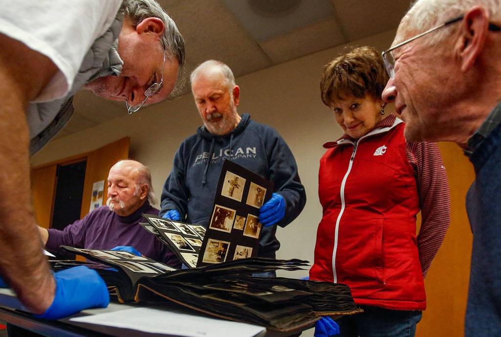 Nothing like getting a bunch of historians and history buffs together to look at scrapbooks and old photo albums. From left, Allan White, Dave Ramstad, Jack ODonnell, Janice White and Jerry Solie do just that Tuesday night at the Everett Public Library. (Dan Bates / The Herald)