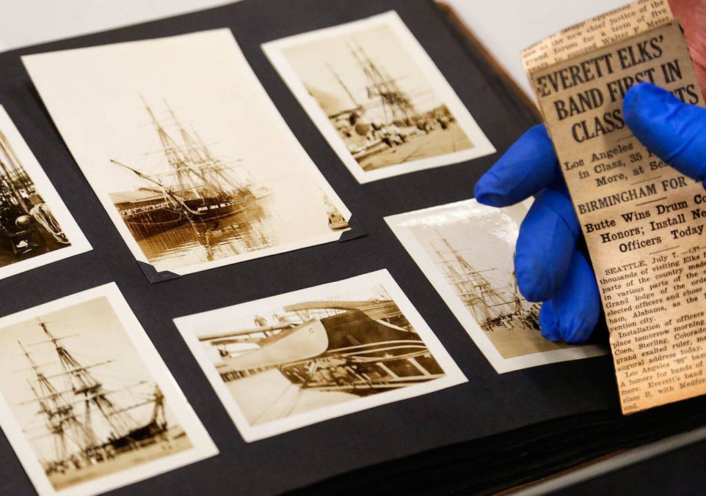Although engrossed in pictures of Old Ironsides, William Vincent pauses to read a vintage newspaper clipping handed to him by Jerry Solie. It is about the Everett Elks Band winning an award. (Dan Bates / The Herald)