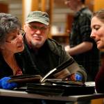 The Everett Public Librarys History-Mystery night drew a number of photo sleuths eager to look at old scrapbooks and try to identify people and places from the past. Here, Judy Brackett (left) and Steve Hudspeth look over some very old scrapbook items as the librarys Northwest Room historian, Lisa Labovitch (right), looks on. (Dan Bates / The Herald)