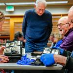 From left, library historian Lisa Labovitch, Jerry Solie (standing), and history buffs Dave Ramstad and William Vincent (right) enjoy one anothers light conversation while studying images in dozens of scrapbooks and photo albums Tuesday night at the Everett Public Library. (Dan Bates / The Herald)