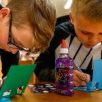 Carter Howell, 12, (left) from Post Middle School, and Bjorn Gudgeon, 12, from Haller Middle School print messages on pop-up cards they made during a card-making party at Arlington Library April 12. The cards were to be sent to the nonprofit Cards for Hospitalized Kids. (Dan Bates / The Herald)