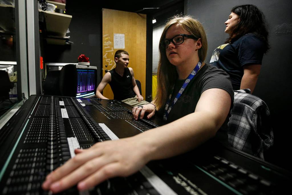 Kamiak High School senior Sydney Erickson adjusts stage light levels to complement the script. (Ian Terry / The Herald)