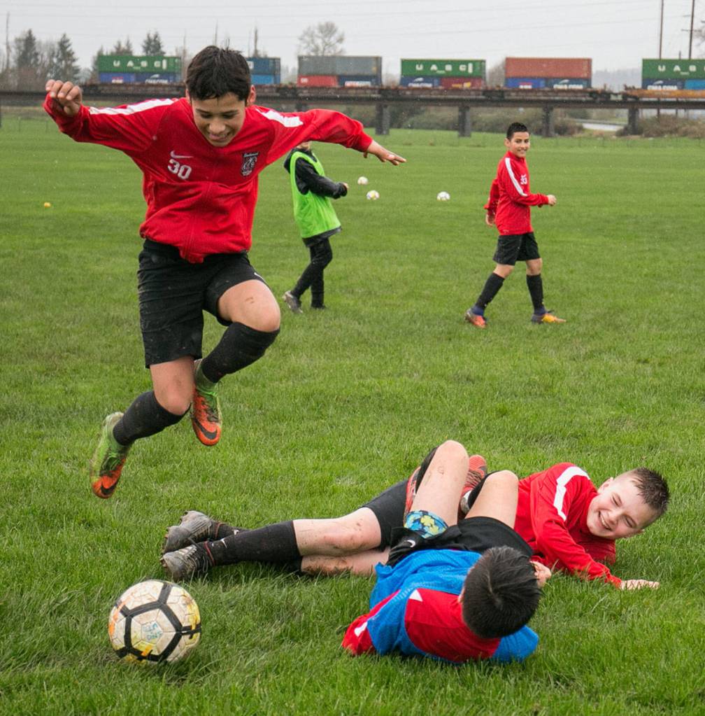 Gerardo Avalos-Ayala (left) hurdles over Cason Chadd (top) and Acxel Gonzalez-Lara (bottom) after the latter two players collided during a Snohomish Youth Soccer Club Development Academy scrimmage at Stocker Fields on April 5 in Snohomish. (Kevin Clark / The Daily Herald)