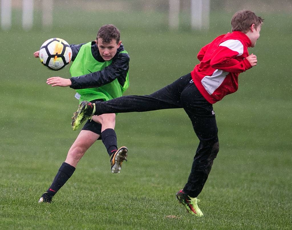 Alden Pate (left) kicks a ball while Gabriel Esterly defends during a Snohomish Youth Soccer Club Developement Academy scrimmage on April 5 at Stocker Fields in Snohomish. (Kevin Clark / The Herald)