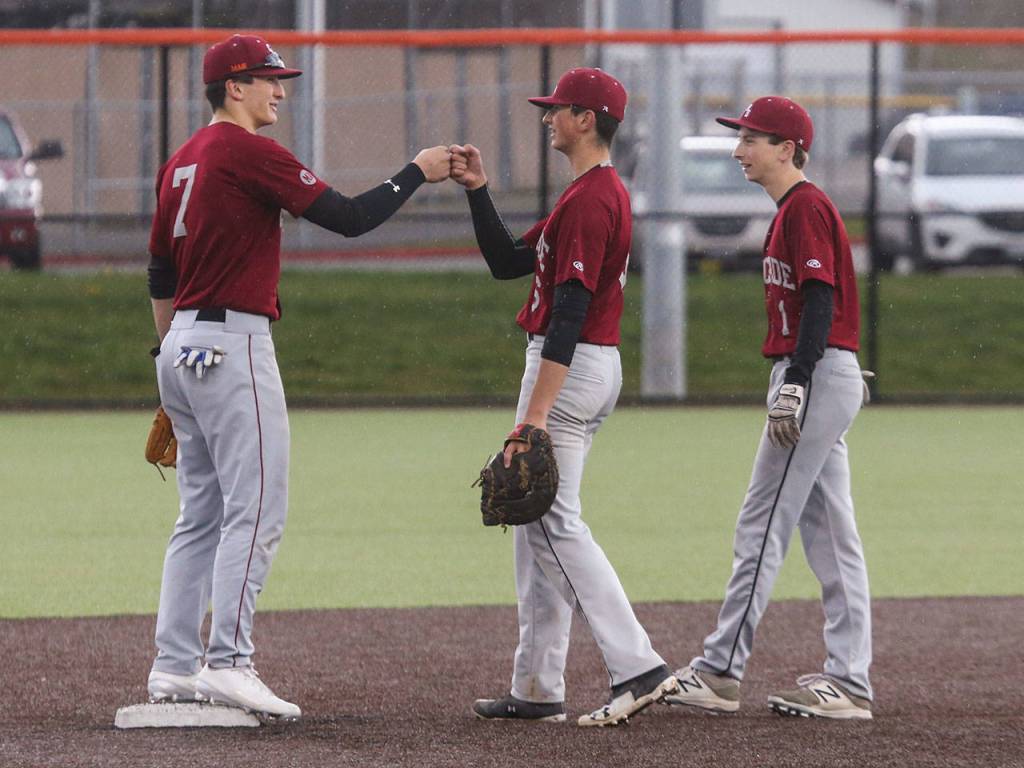 Cascades Brett Gillis (left) fist bumps his brother, pitcher Brock Gillis, after Brock is relieved by Benjamin Hansen (right) in the seventh inning of a game against Monroe on April 17, 2018, in Monroe. (Andy Bronson / The Herald)
