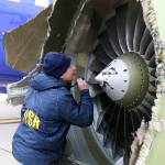 A National Transportation Safety Board investigator examines damage to the engine of the Southwest Airlines plane that made an emergency landing at Philadelphia International Airport in Philadelphia. (NTSB via AP)