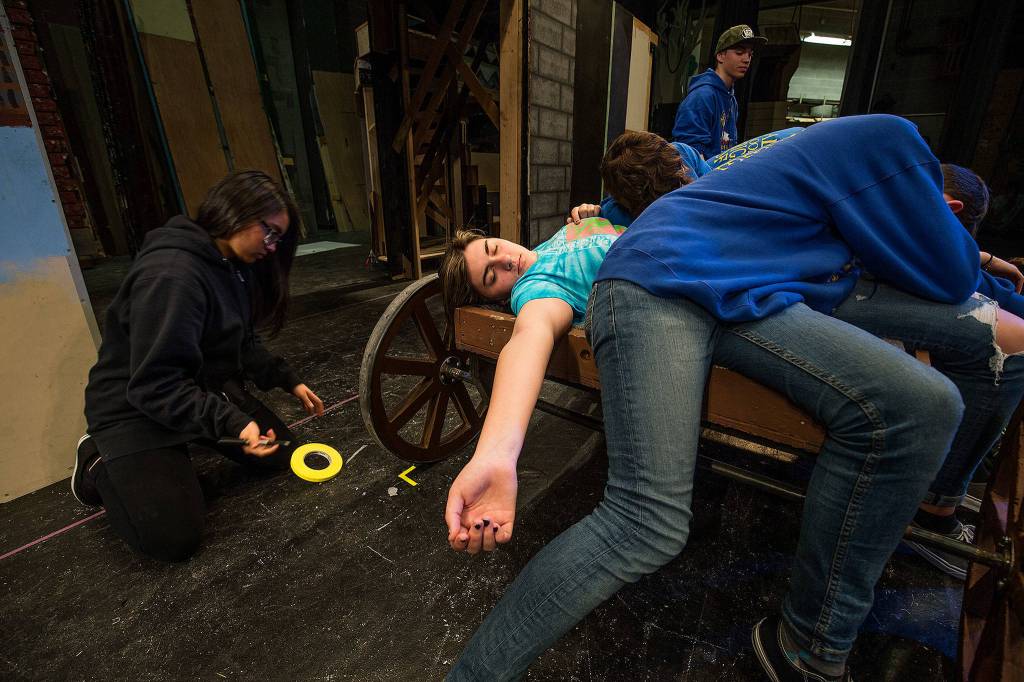 Assistant stage manager Jonna Alonso marks the position of a cart carrying the dead during a rehearsal. (Andy Bronson / The Herald)