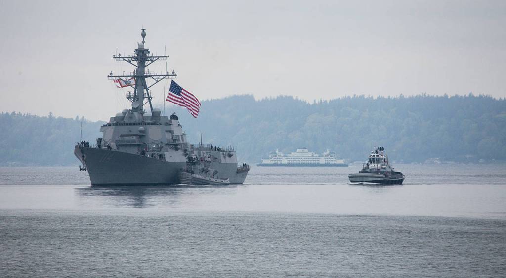 A state ferry passes in the background as the Navy destroyer USS Ralph Johnson arrives at Naval Station Everett on Friday. (Andy Bronson / The Herald)