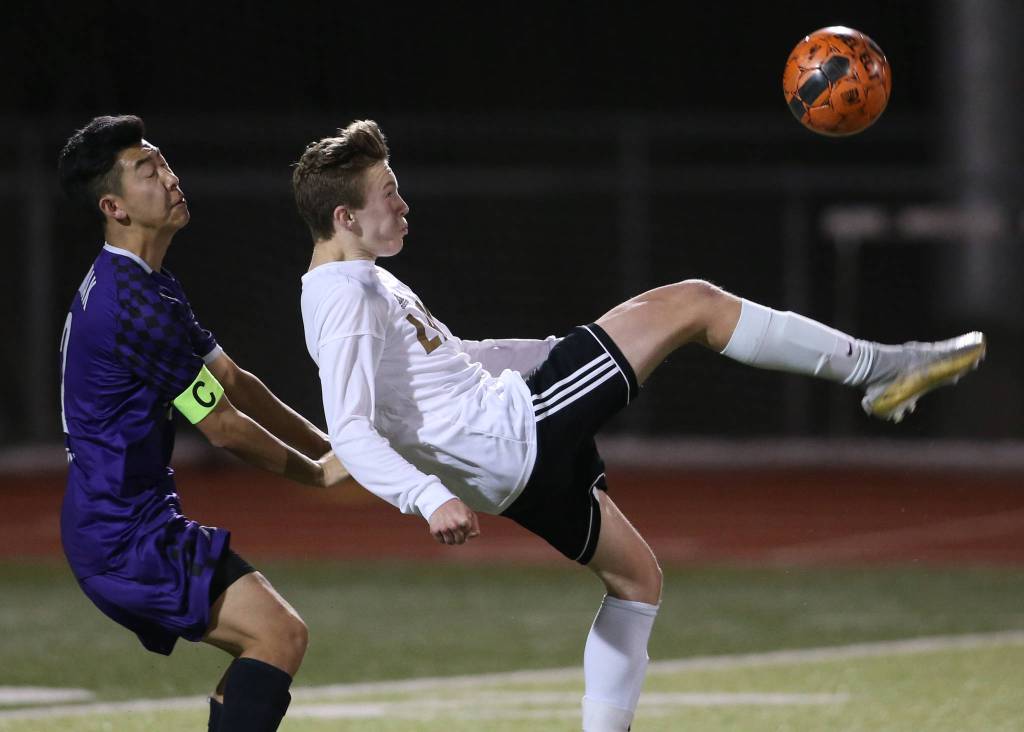 Lake Stevens Jackson Busby kicks the ball back over the head of Kamiaks Joshua Pang on April 24 in Lake Stevens. (Andy Bronson / The Herald)