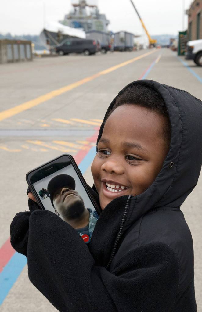 Kurt Littlejohn, 2, holds a cell phone showing his fathers face as they FaceTime while the Navy destroyer <a href="http://www.heraldnet.com/news/a-brand-new-destroyer-arrives-at-its-home-port-of-everett/" target="_blank">USS Ralph Johnson docks at Naval Station Everett</a> on April 27. (Andy Bronson / The Herald)