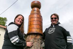 Roxy and Illiad Gesler have a chainsawed Stanley Cup model carved of cedar atop a stump in the front yard of their home on May 10, 2018. (Kevin Clark / The Herald)