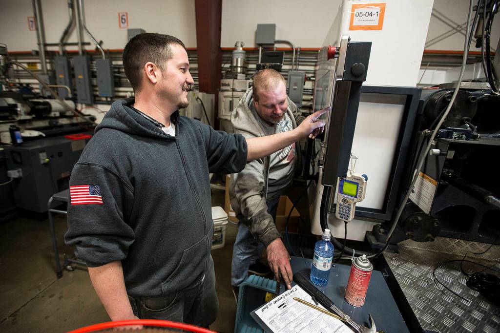 Ronnie Bowers (left) and Mark Rhodes set up an injection molding machine at Sea-Lect Plastics in Everett. (Ian Terry / The Herald)